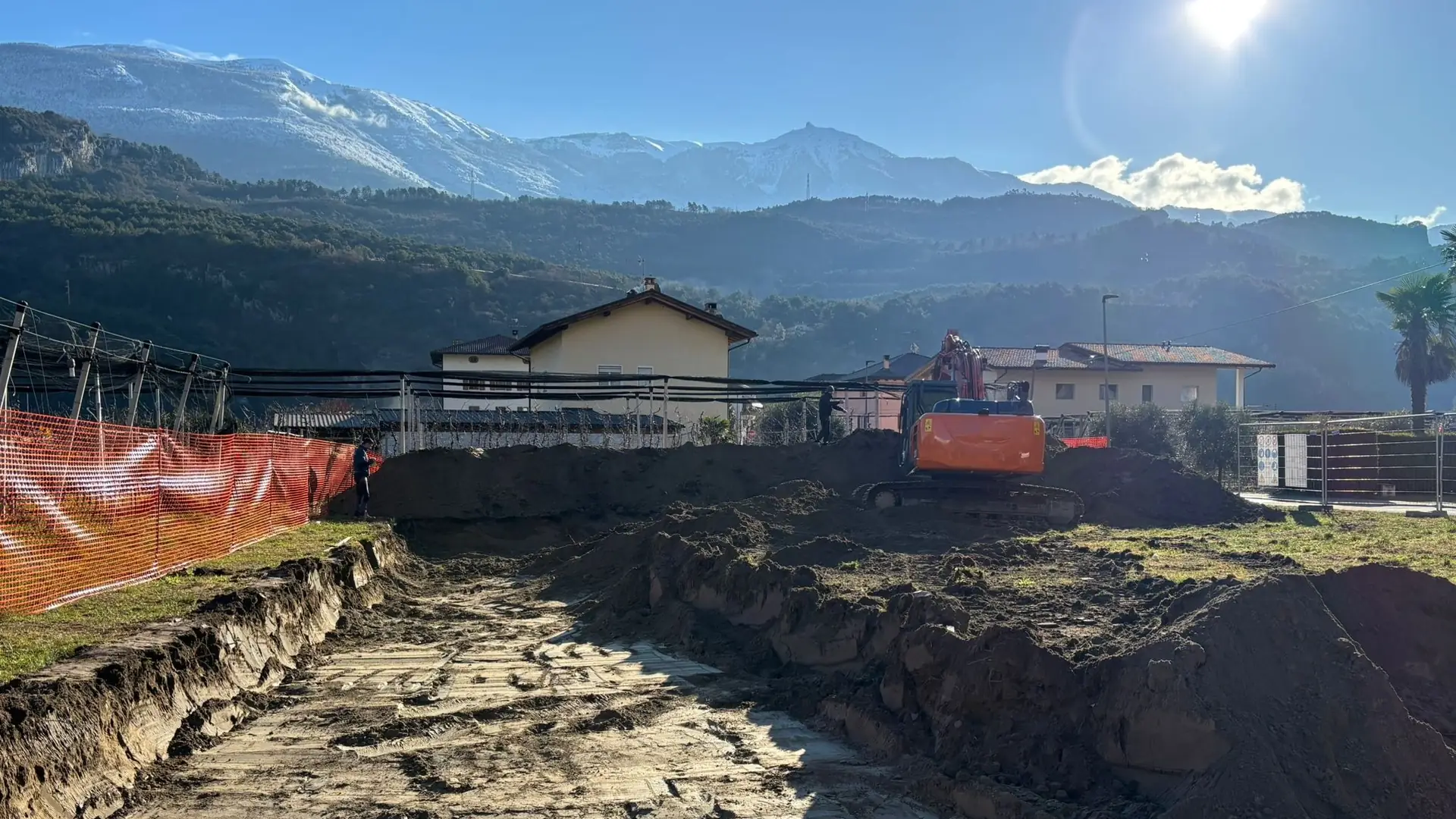 Scavo per una nuova costruzione con le montagne del Trentino sullo sfondo