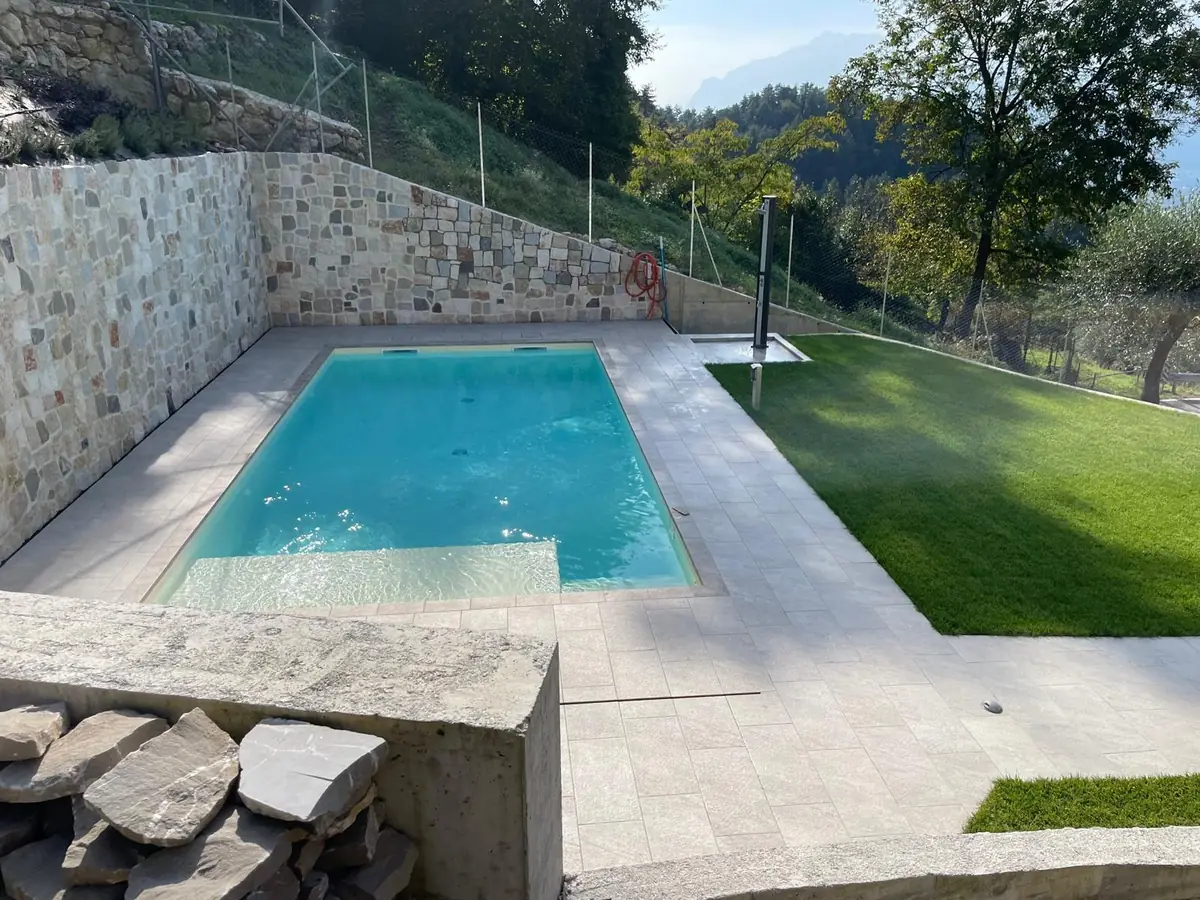 Piscina con bordo in pietra e muro di contenimento